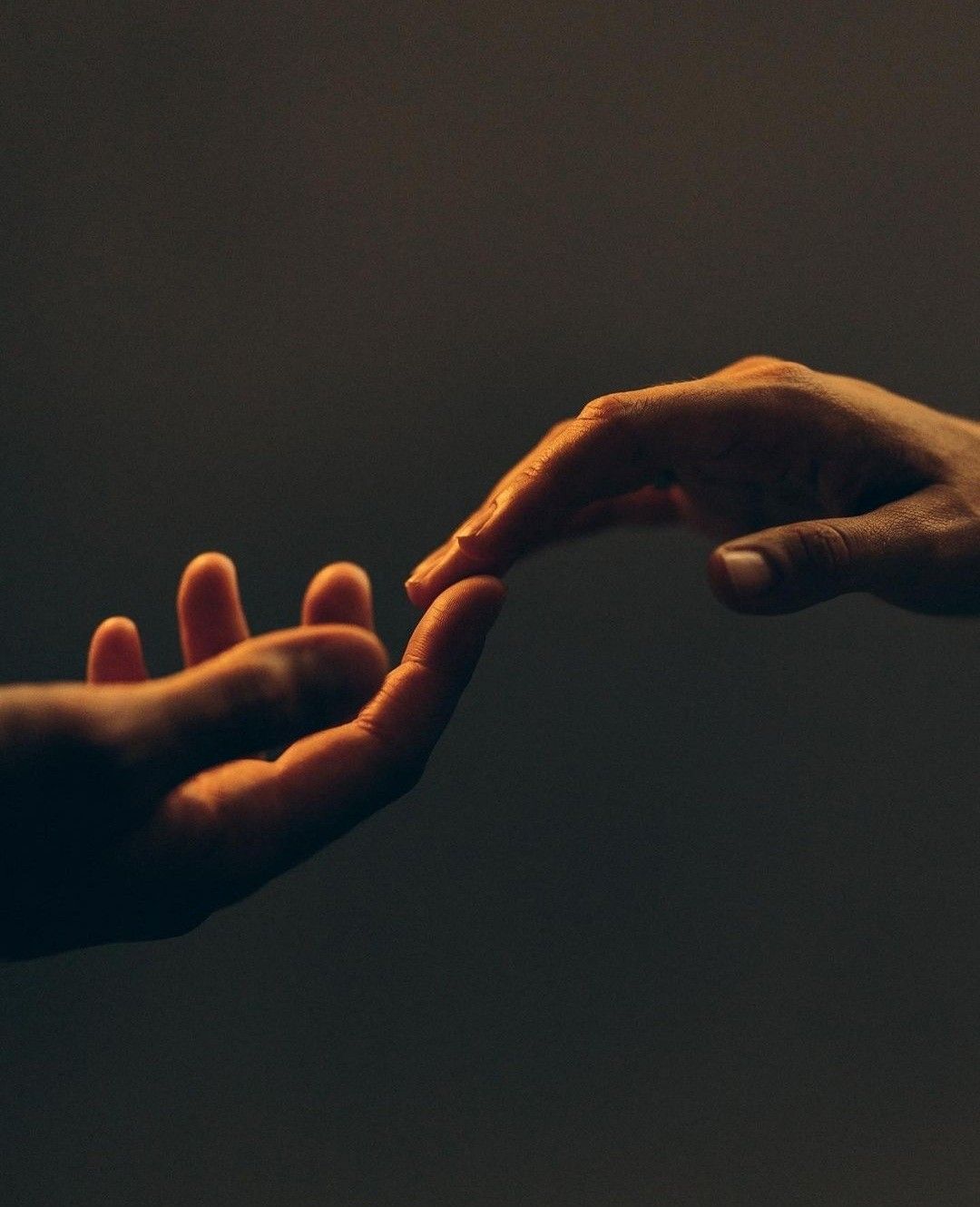 Two hands reaching toward each other in warm golden light